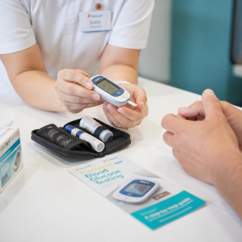 Pharmacist showing a patient how to use a blood glucose monitor during a Diabetes MedsCheck